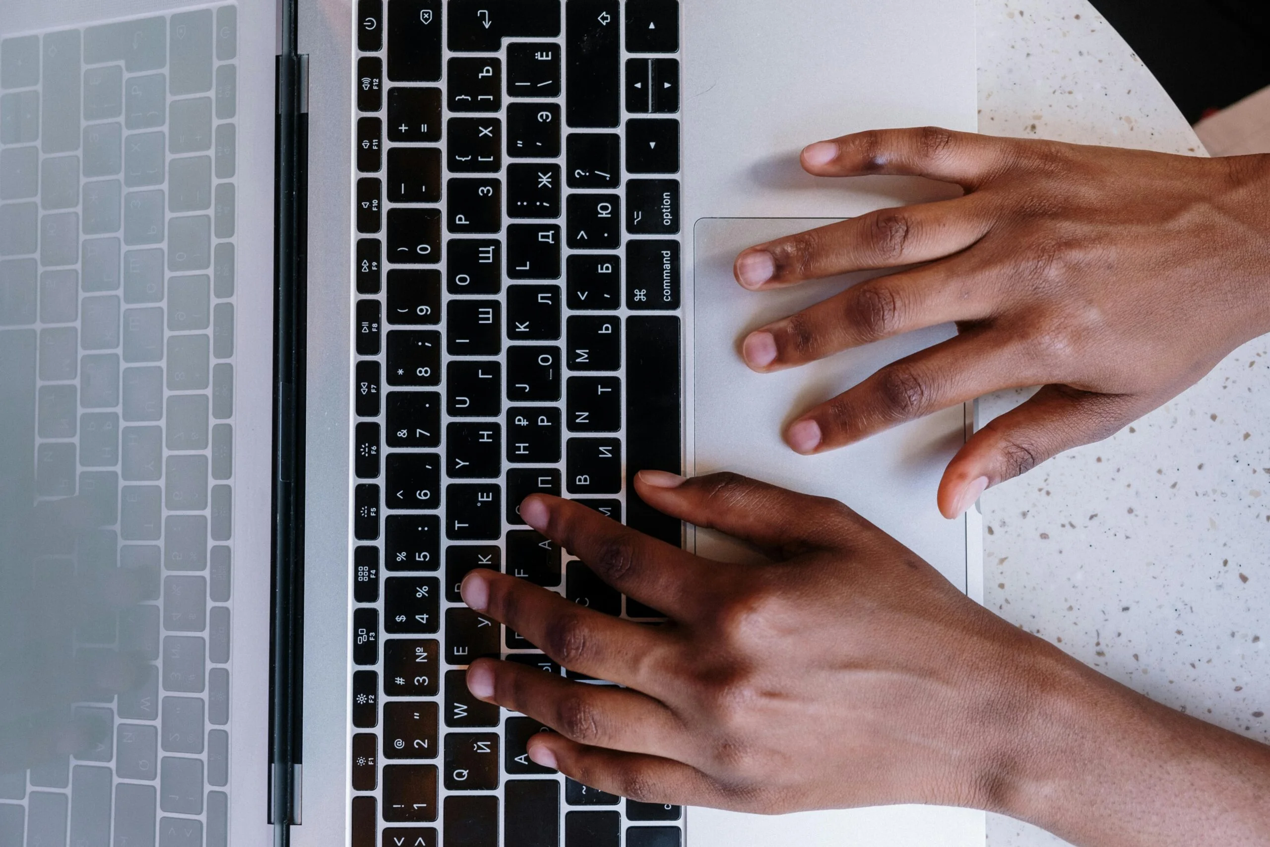 Person typing on a laptop keyboard, focusing on remote work and productivity.
